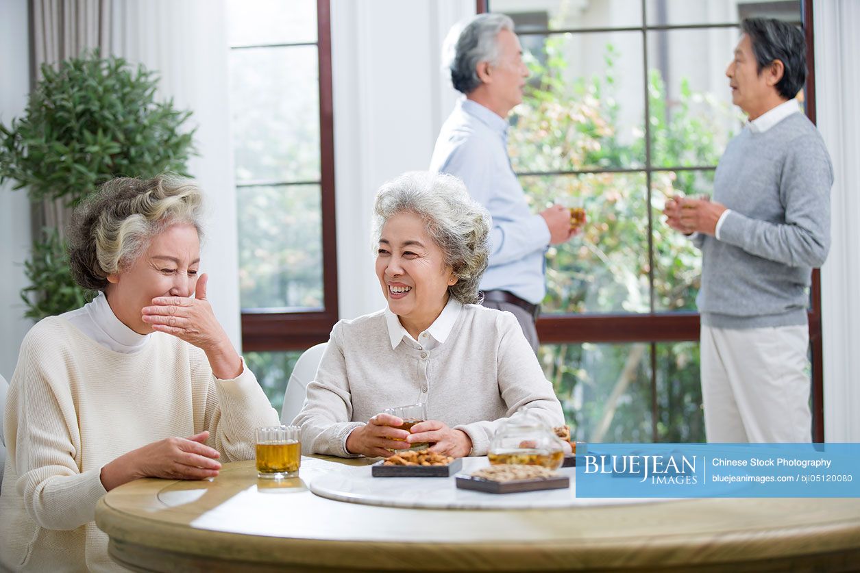 Happy senior Chinese friends talking and drinking tea