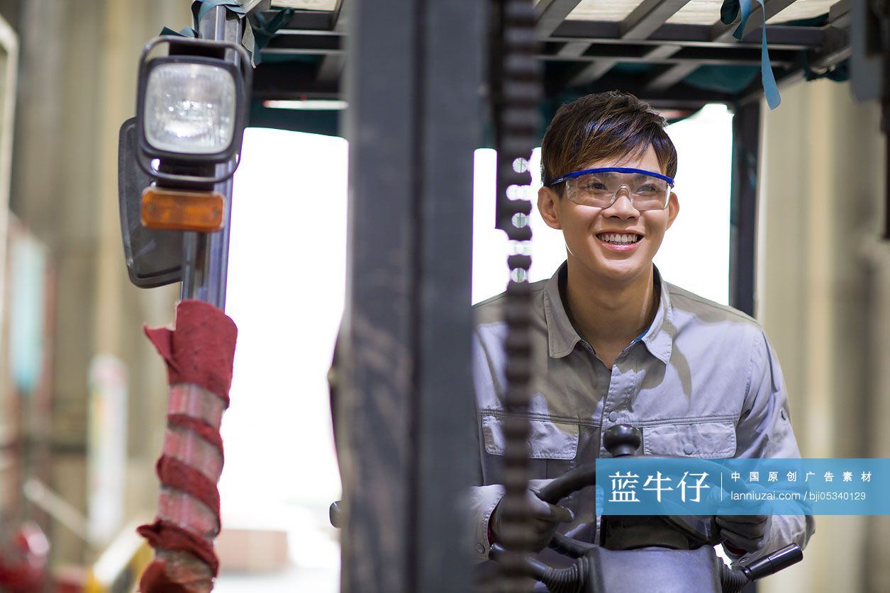 年轻工人在工厂里驾驶叉车