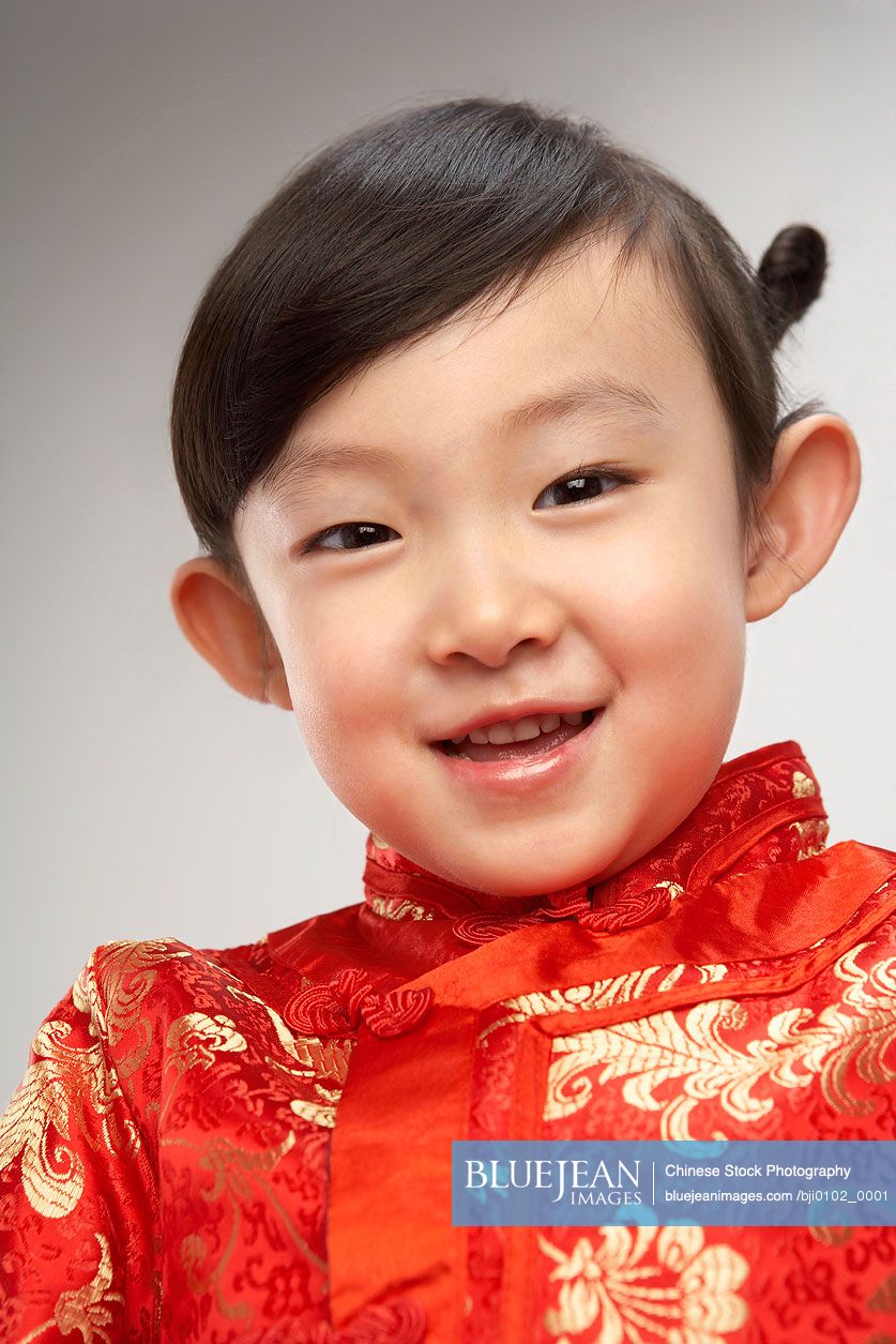 Portrait of young Chinese girl in festival Chinese New Year clothing, smiling at camera