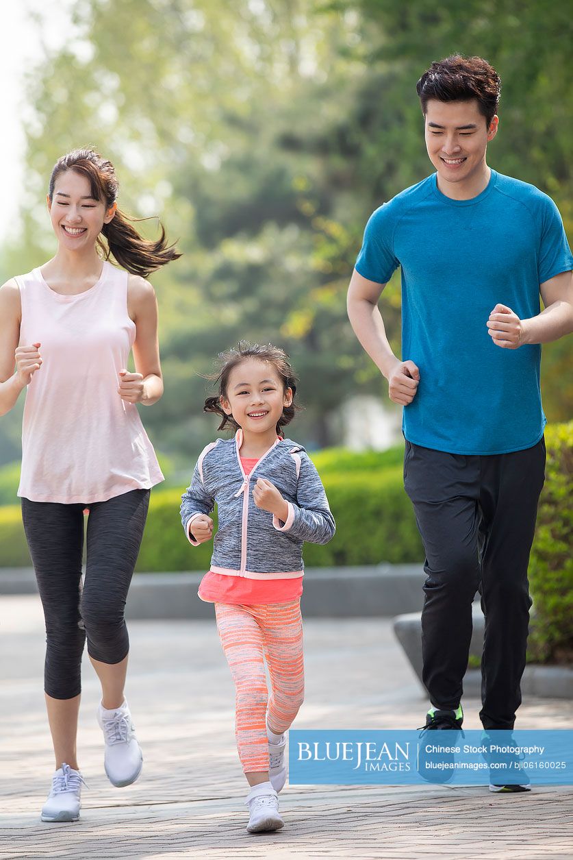 Happy young Chinese family running in park