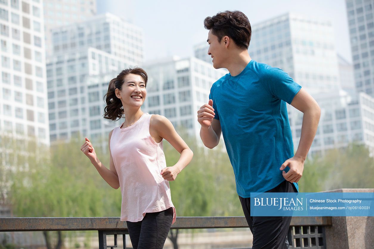 Happy young Chinese couple running in park
