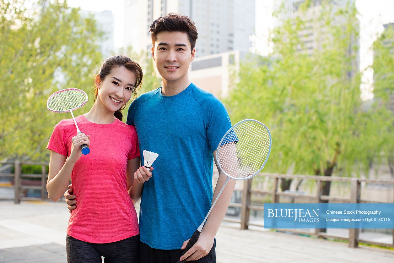 Happy young Chinese couple playing badminton in park