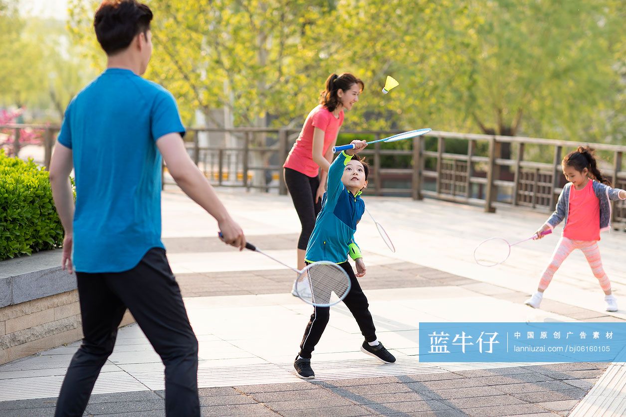 快乐的年轻家庭在公园打羽毛球