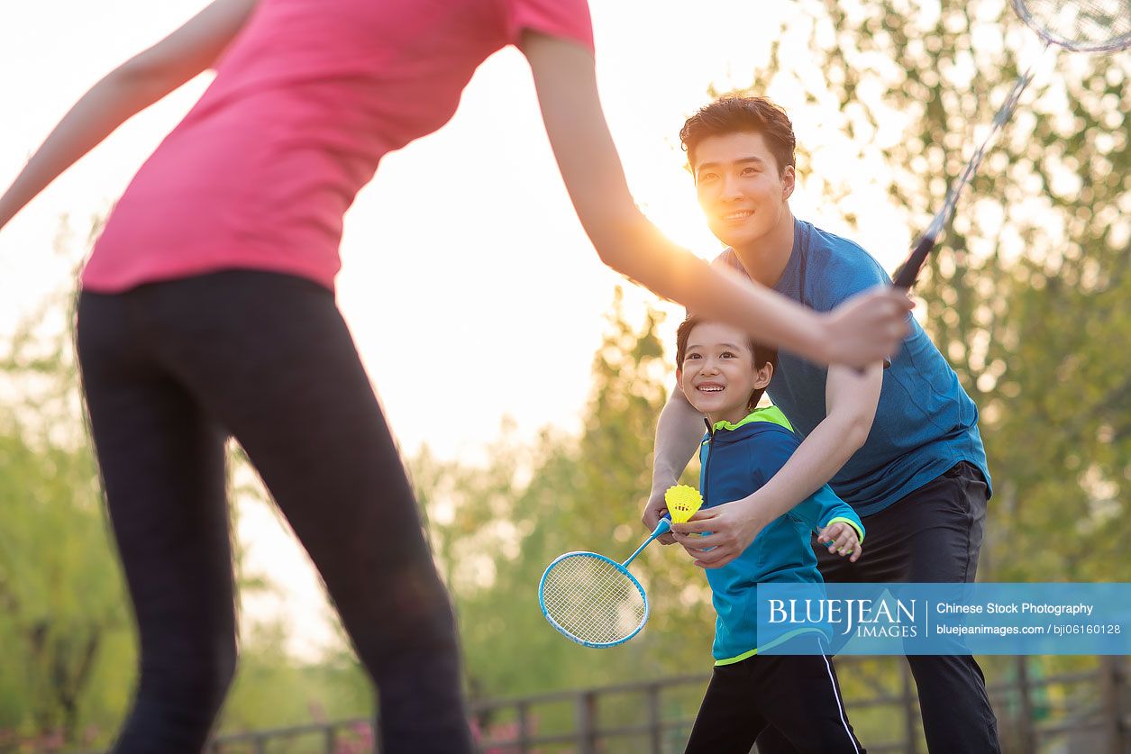Happy young Chinese family playing badminton in park