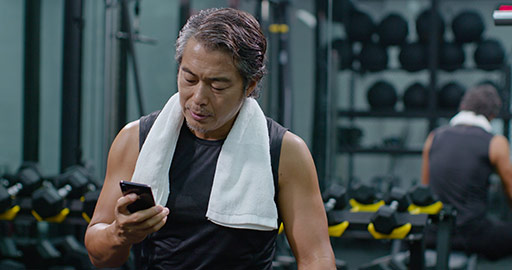 Mature Chinese man using smartphone at gym,4K