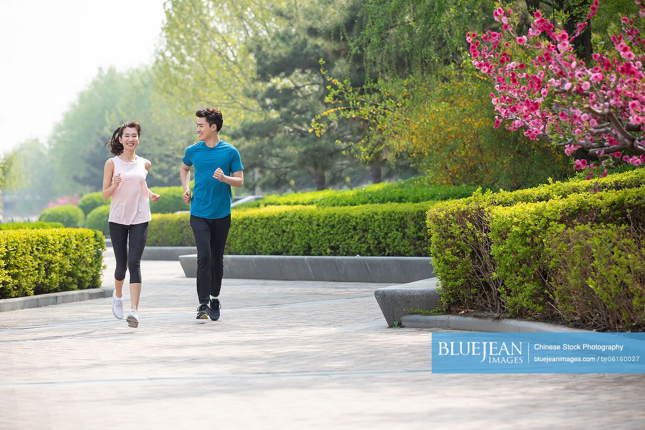 Happy young Chinese couple running in park