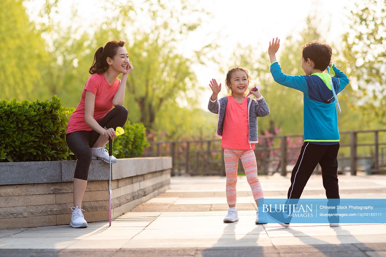 Happy young Chinese family playing badminton in park