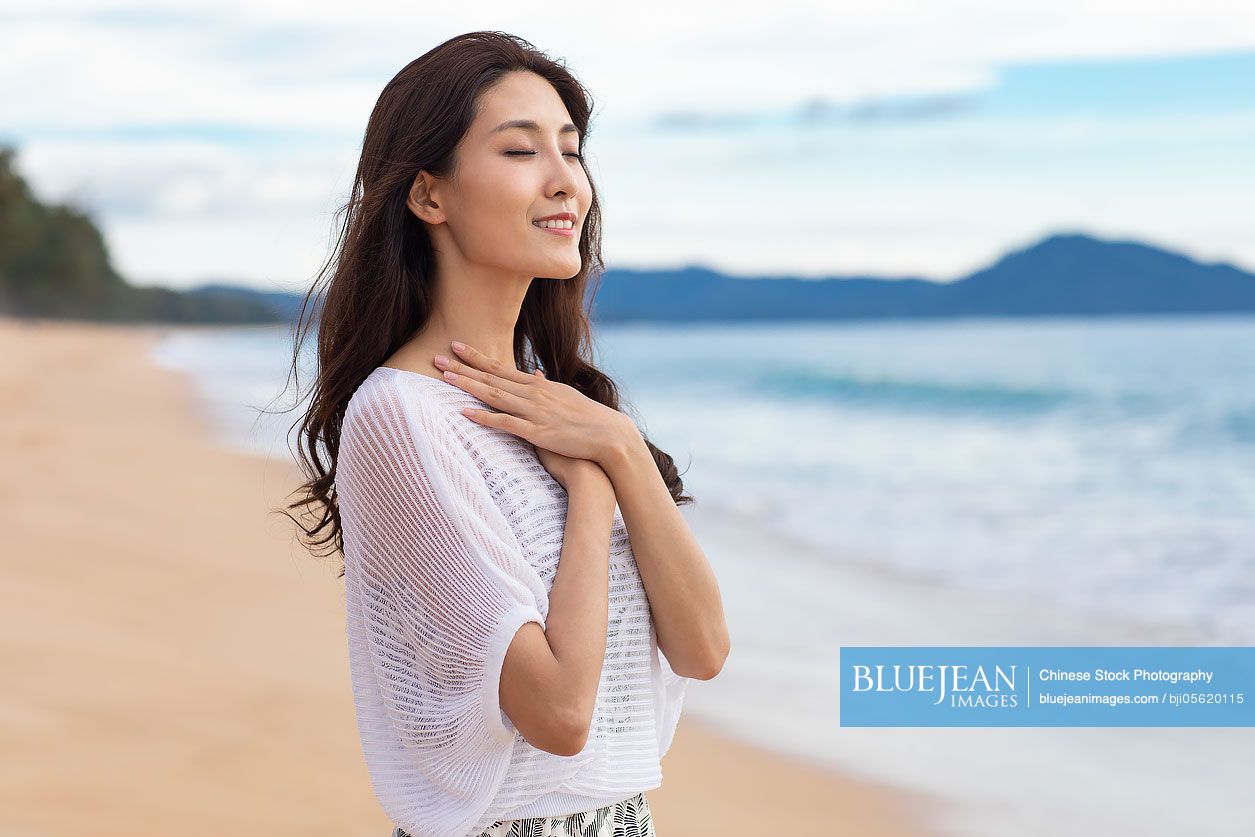Happy young Chinese woman on beach