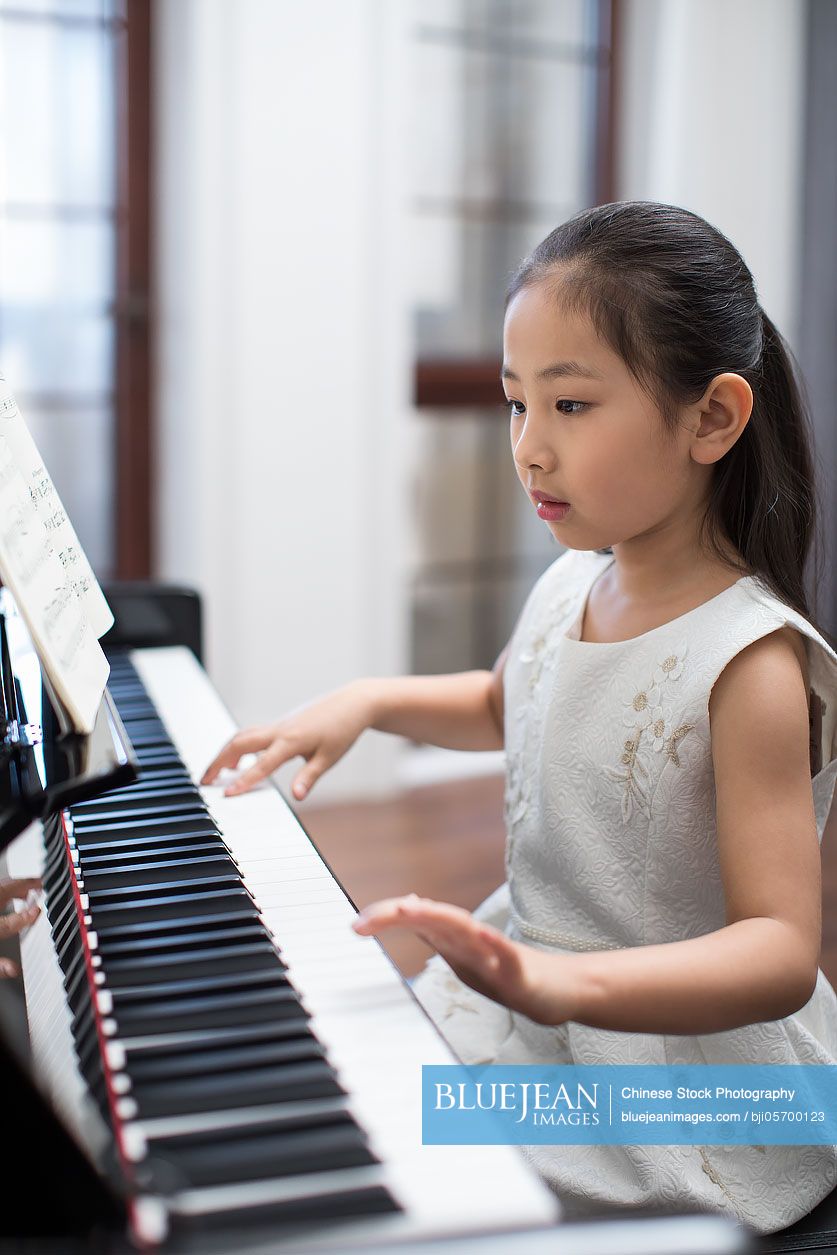 Happy little Chinese girl playing the piano