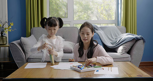 Little girl drawing with her mom by her side