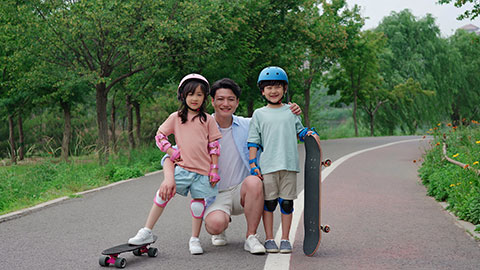 Dad taking kids skateboarding in the park
