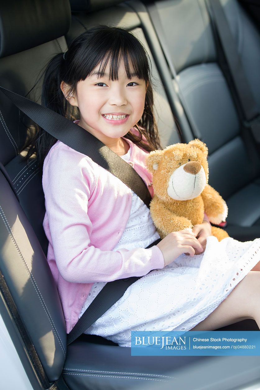 Cute little Chinese girl sitting in car back seat