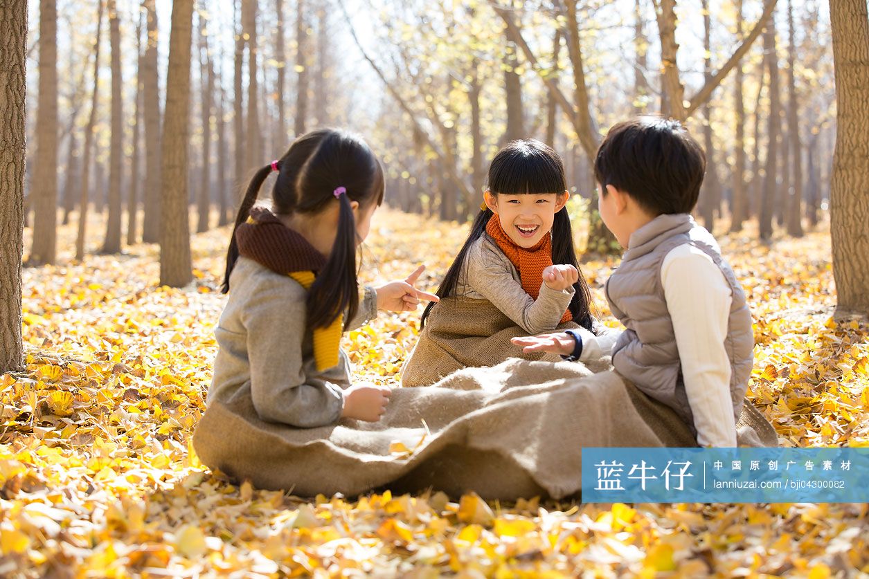 三个小孩在秋日树林里玩剪刀石头布游戏