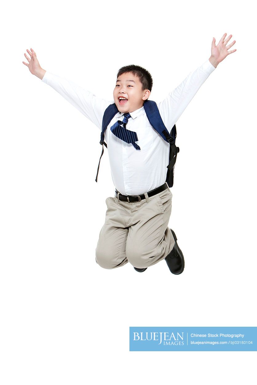 Carefree Chinese schoolboy jumping in mid-air with excitement