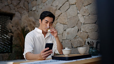 Mid adult Chinese man using smart phone and drinking tea in tea room,4K