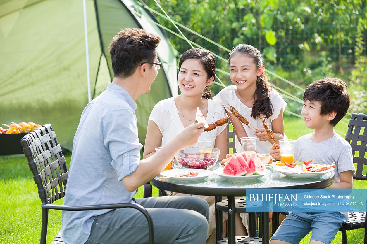 Young Chinese family picnicking outdoors