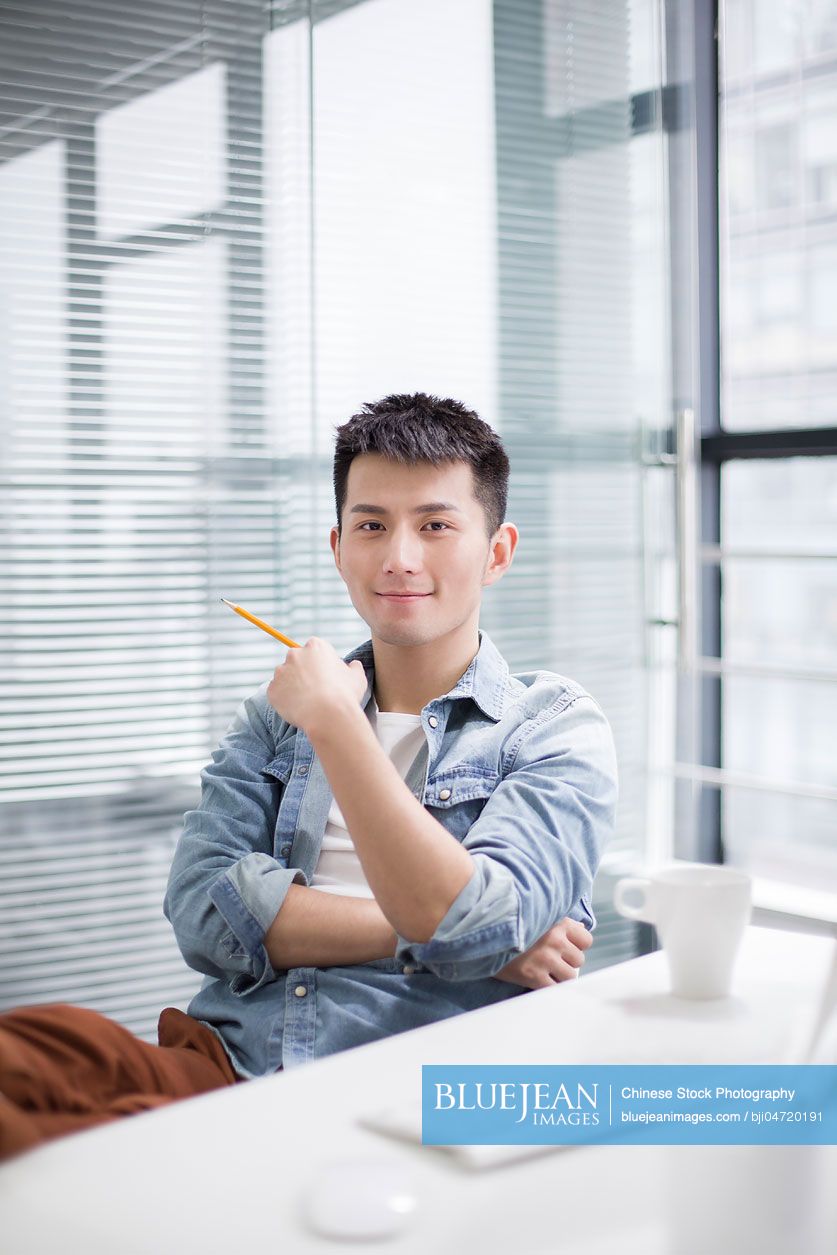 Portrait of young Chinese man in office