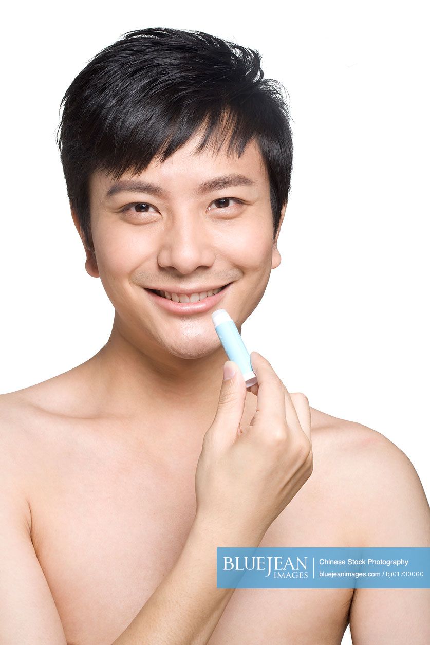 Young Chinese man using lip balm