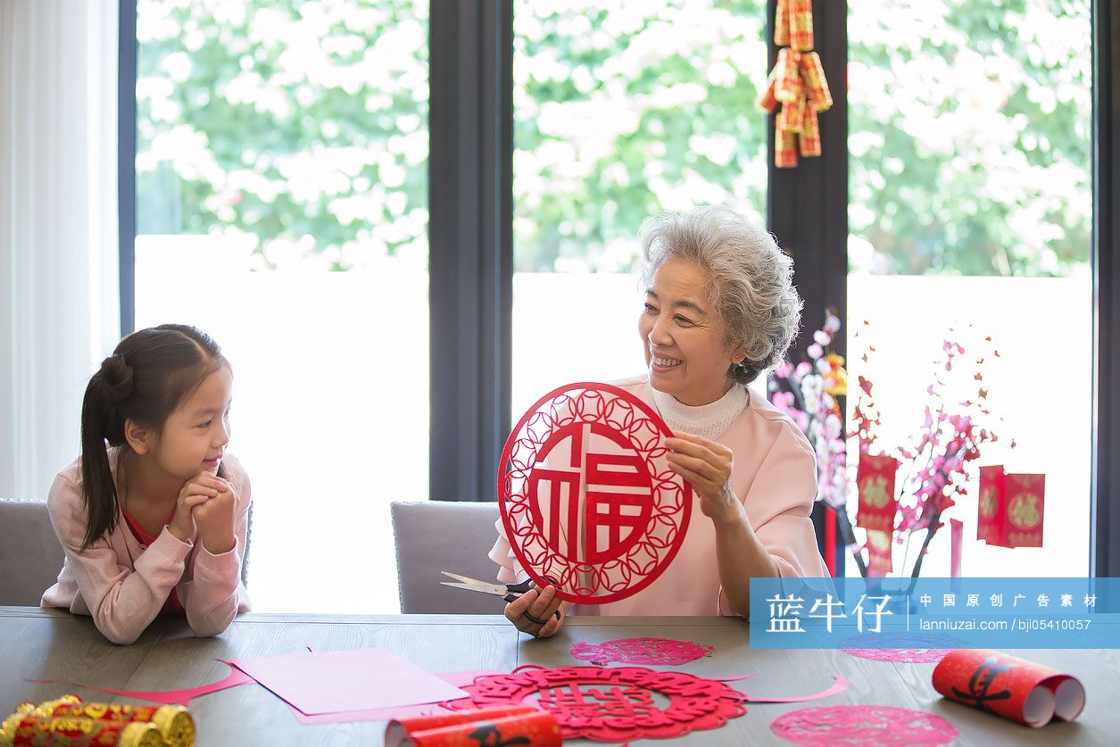 快乐的奶奶教孙女剪新年窗花