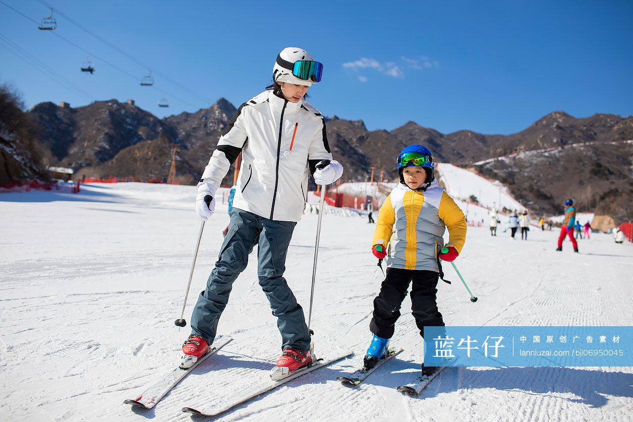 小男孩跟着教练在户外学滑雪