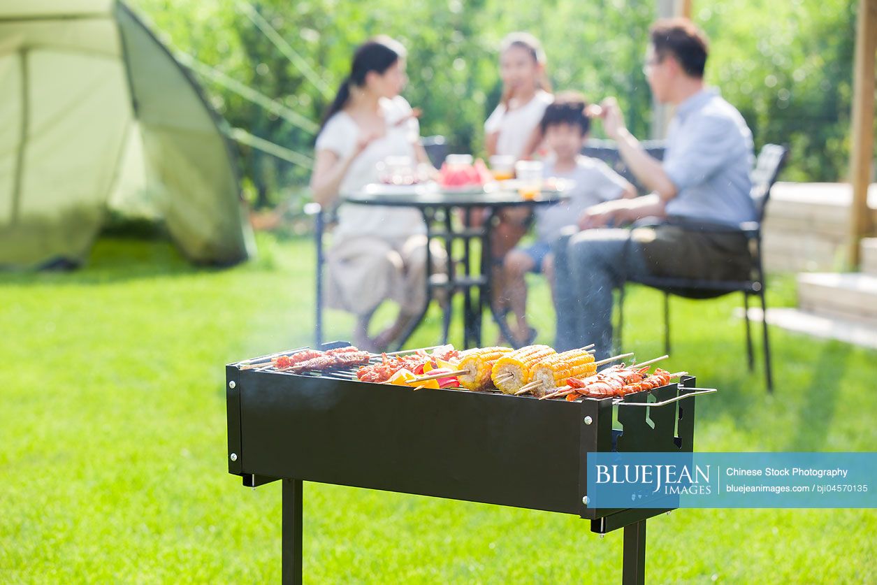 Young Chinese family barbecuing outdoors