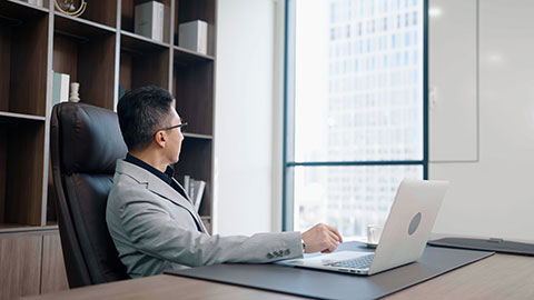 Successful Chinese businessman using laptop in office