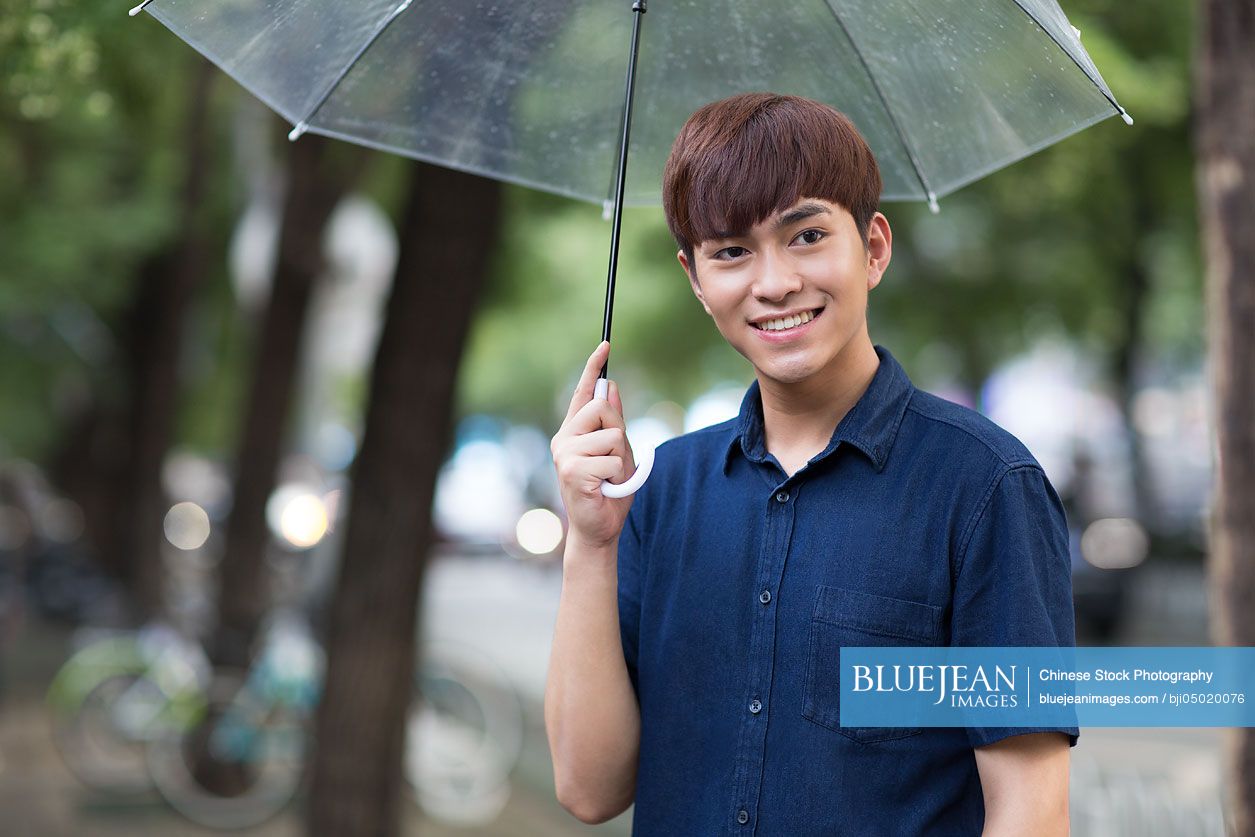 Young Chinese man holding umbrella