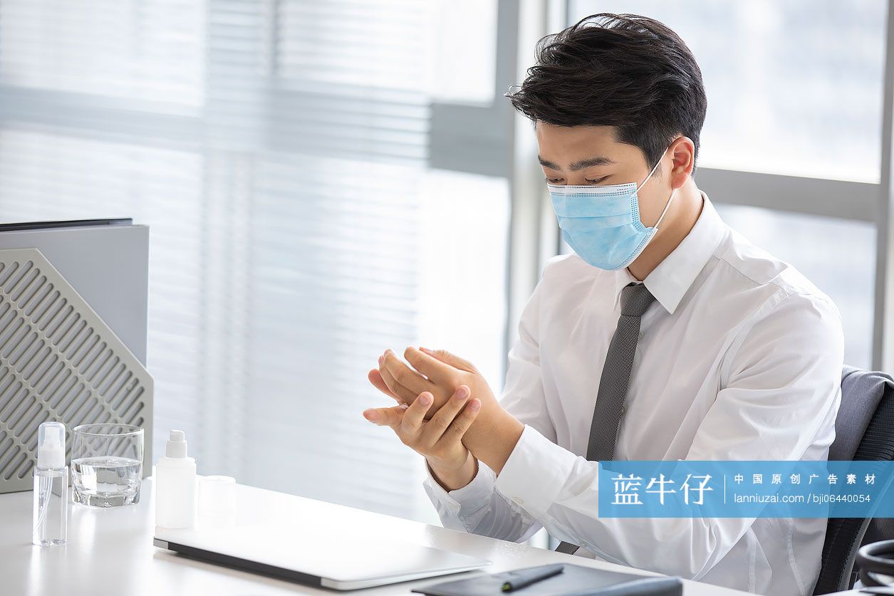 年轻的商务男士在办公室使用免洗洗手液
