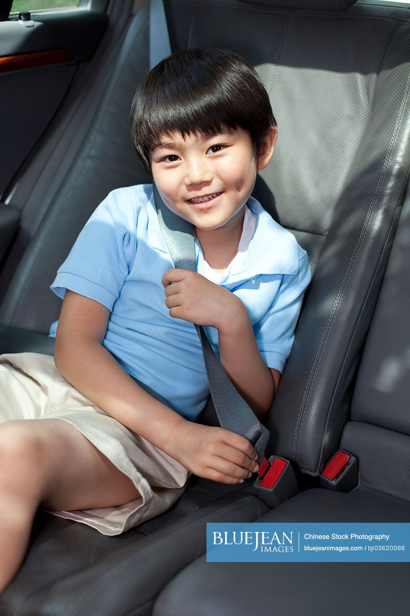 Cute little Chinese boy sitting in car back seat
