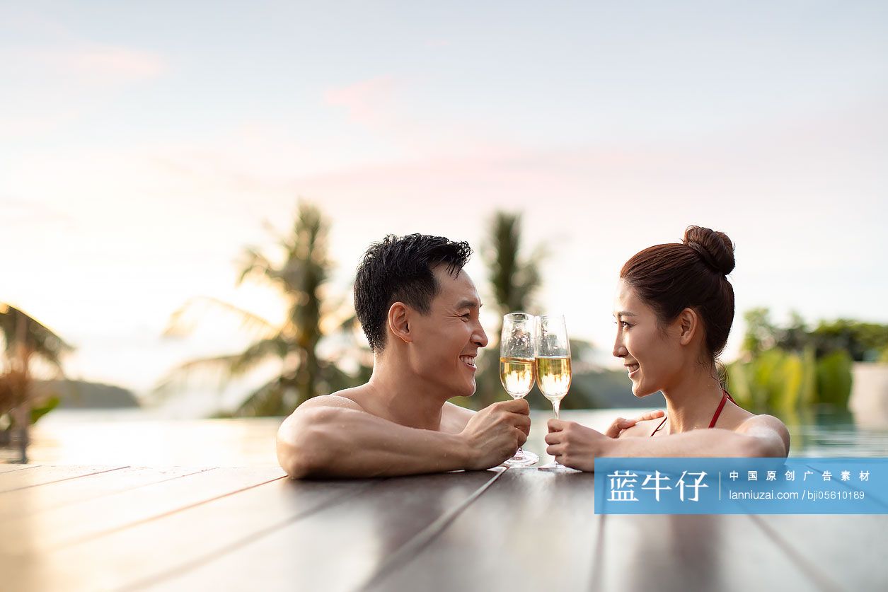 快乐的年轻情侣在泳池边喝香槟