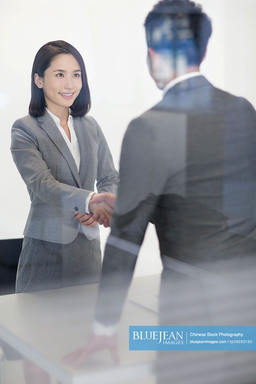 Chinese business person shaking hands in meeting room