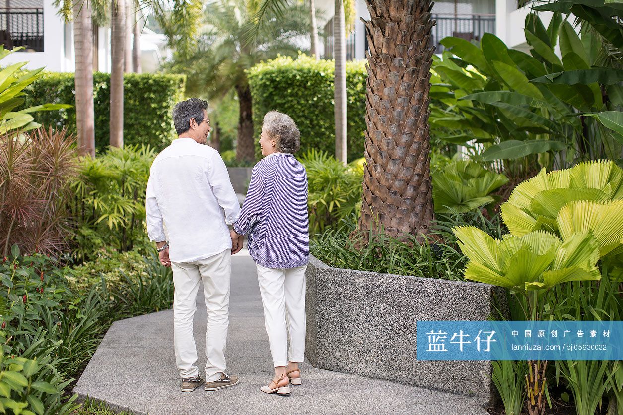 快乐的老年夫妇在庭院牵手散步