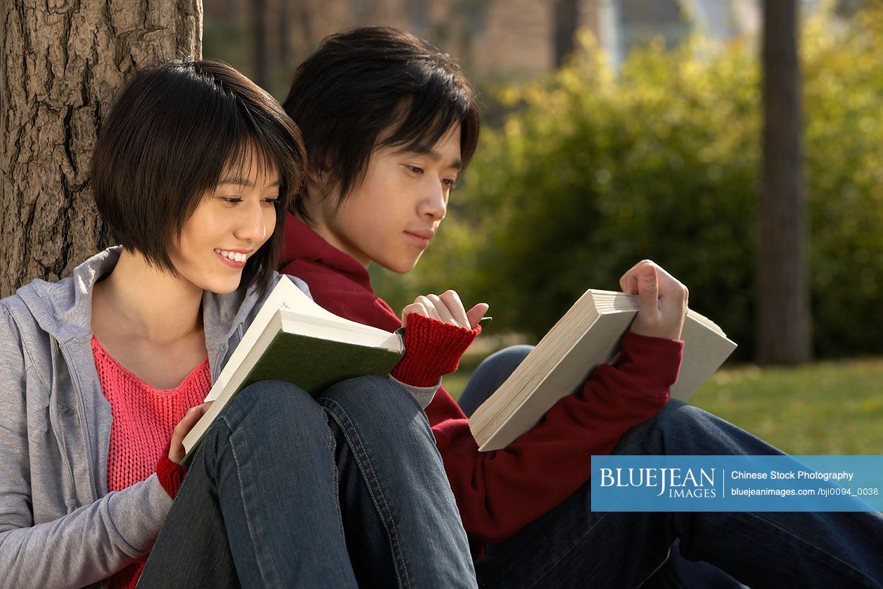 Young Chinese couple reading books in the park