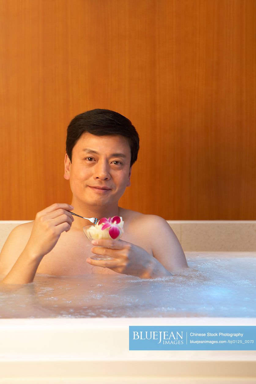 Chinese man relaxing with some fruit in a hot tub