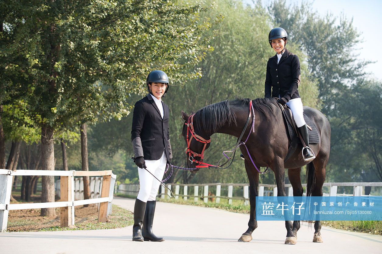 年轻情侣在马场骑马