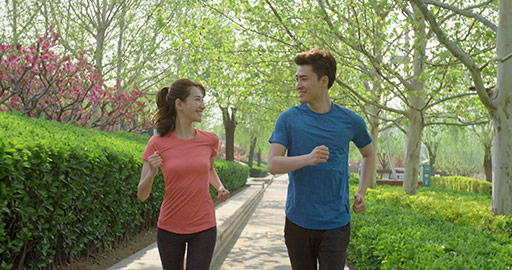 快乐的年轻情侣在公园跑步