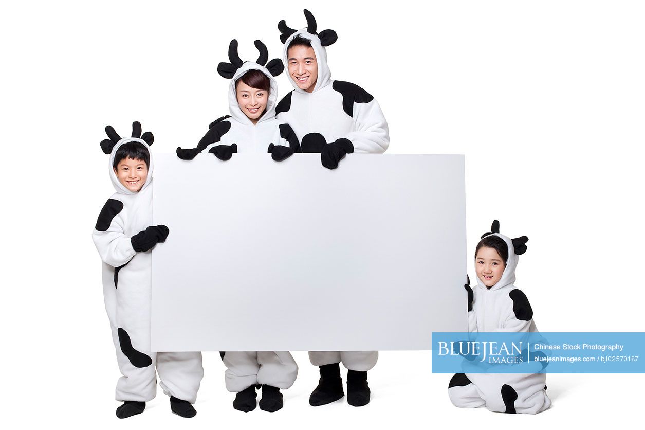 Chinese family in cow costumes holding a blank placard