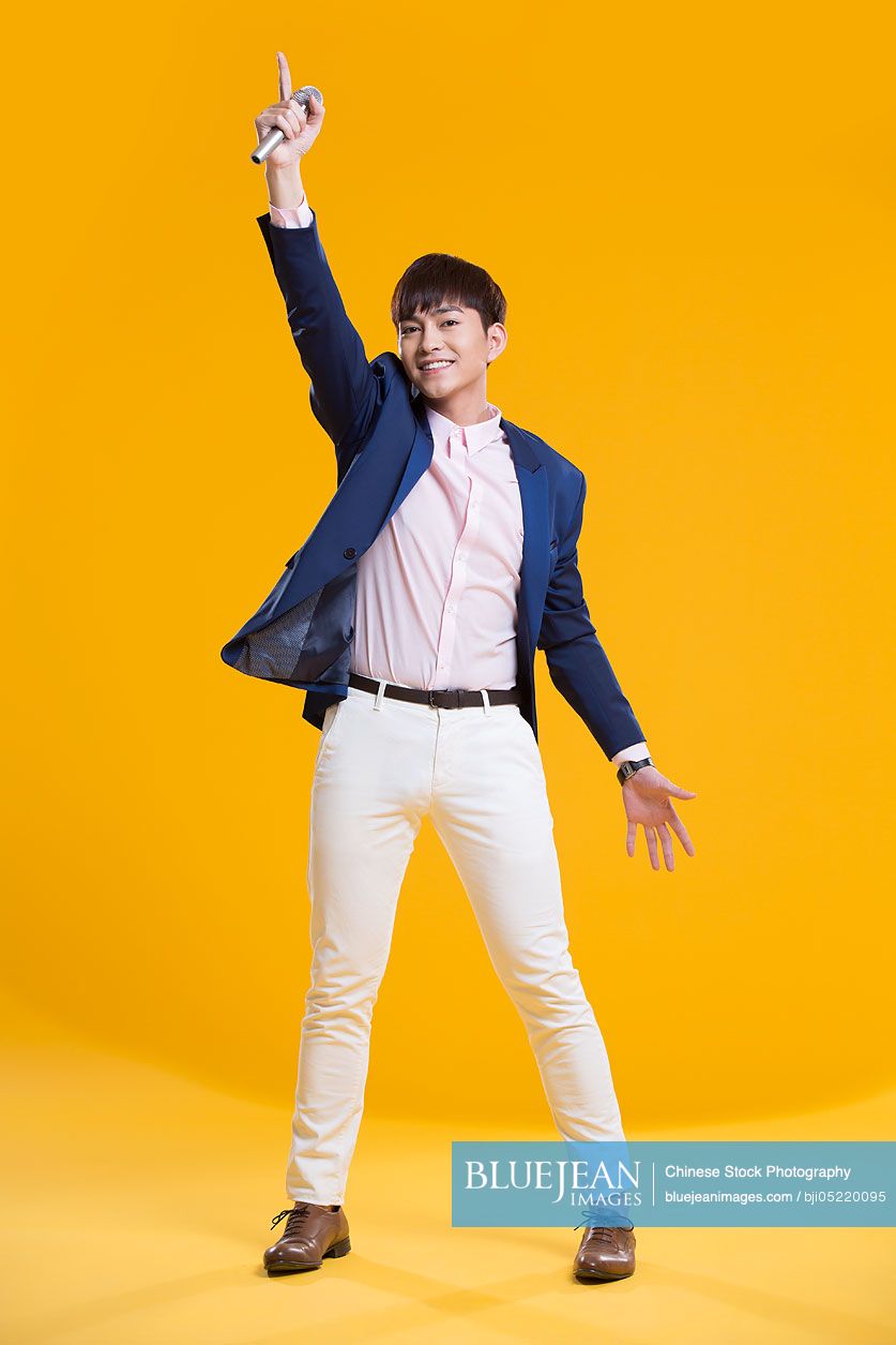 Cheerful young Chinese man singing with microphone