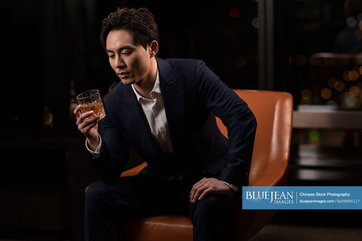 Elegant Chinese man drinking whiskey