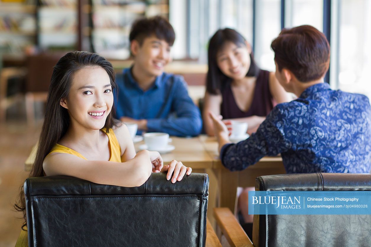 Young Chinese woman drinking coffee with friends in cafe
