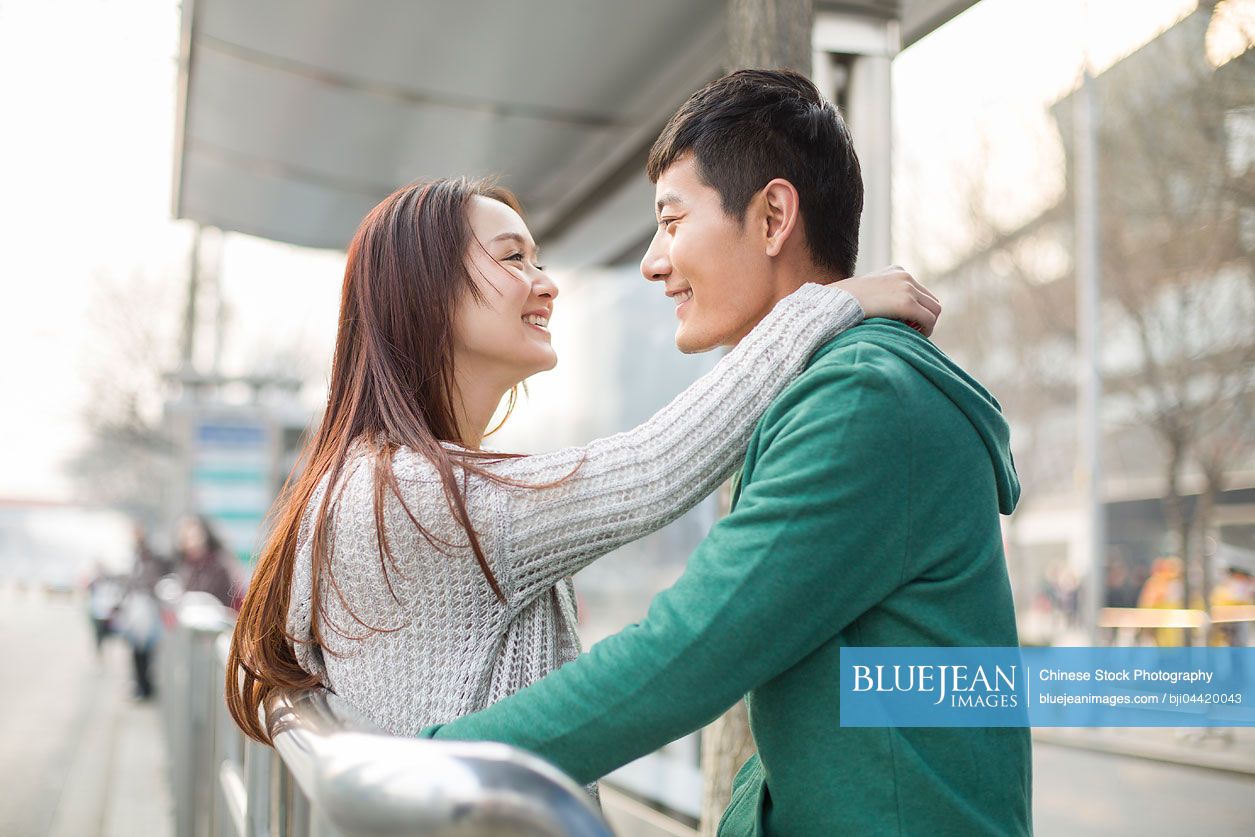 Young Chinese couple waiting at bus stop