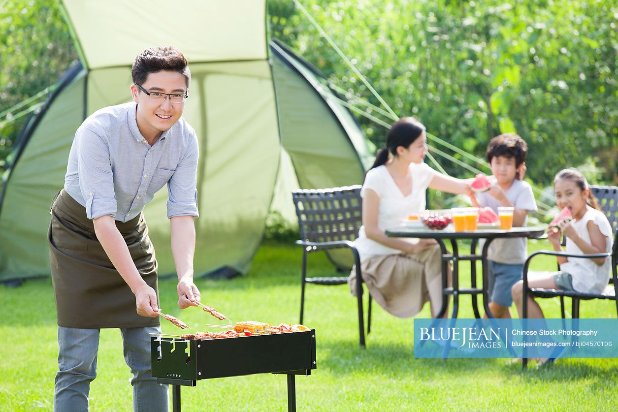Young Chinese family barbecuing outdoors