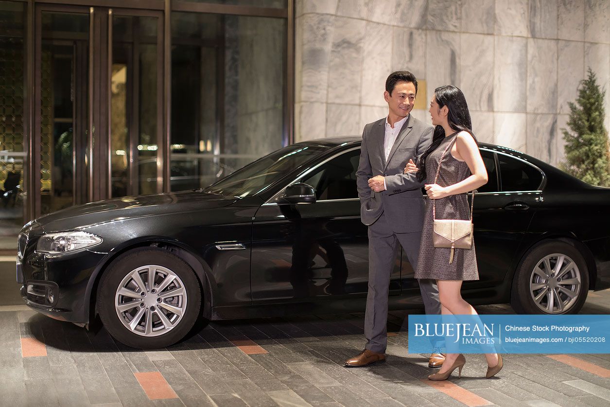 Cheerful young Chinese couple arriving at hotel by car