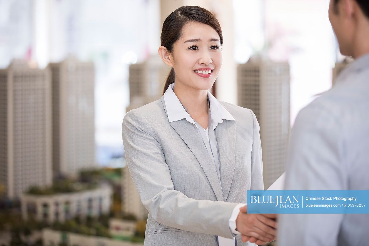 Confident Chinese realtor shaking hands with customer