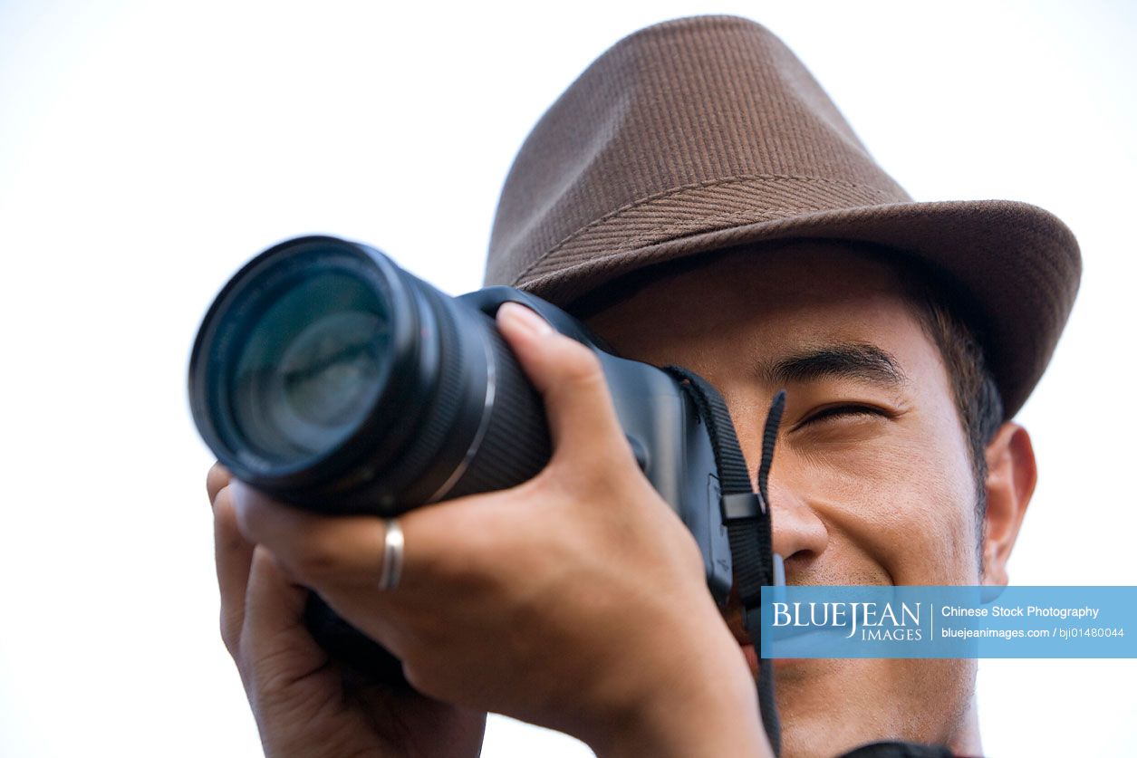 Young Chinese man using camera