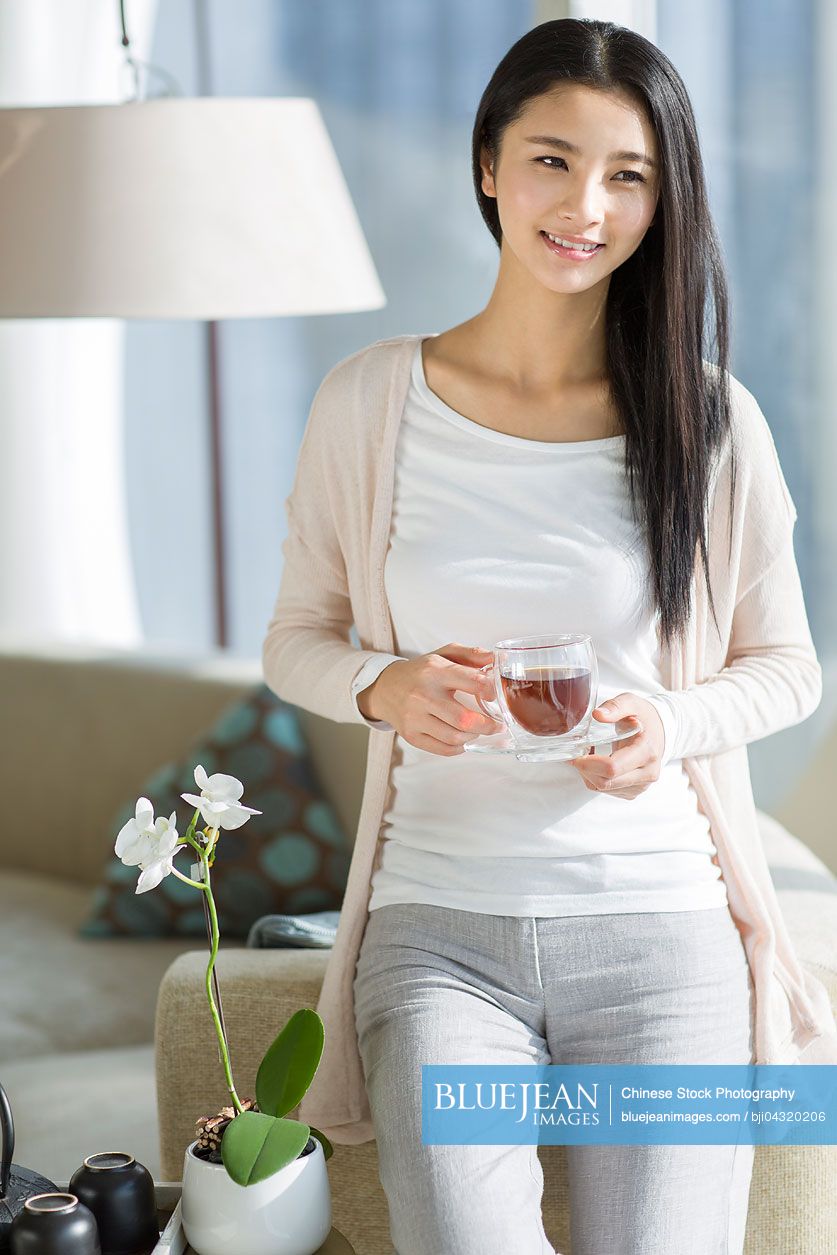 Happy young Chinese woman drinking black tea