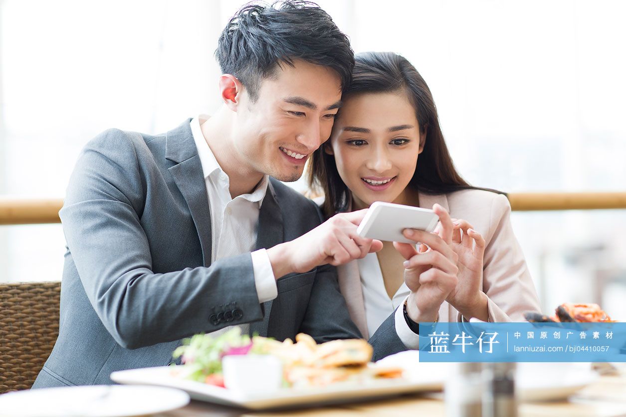 年轻情侣在餐厅里看手机