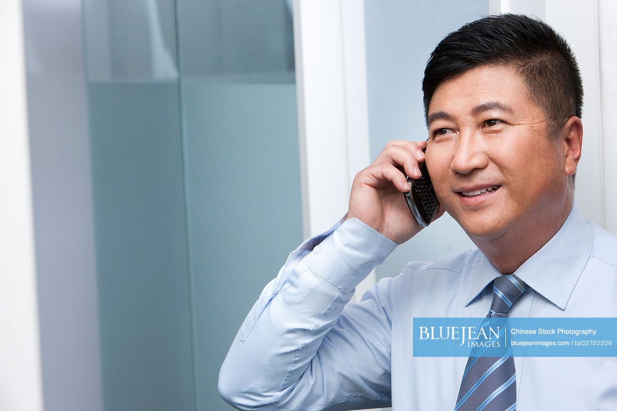 Smiling Chinese businessman on his mobile phone