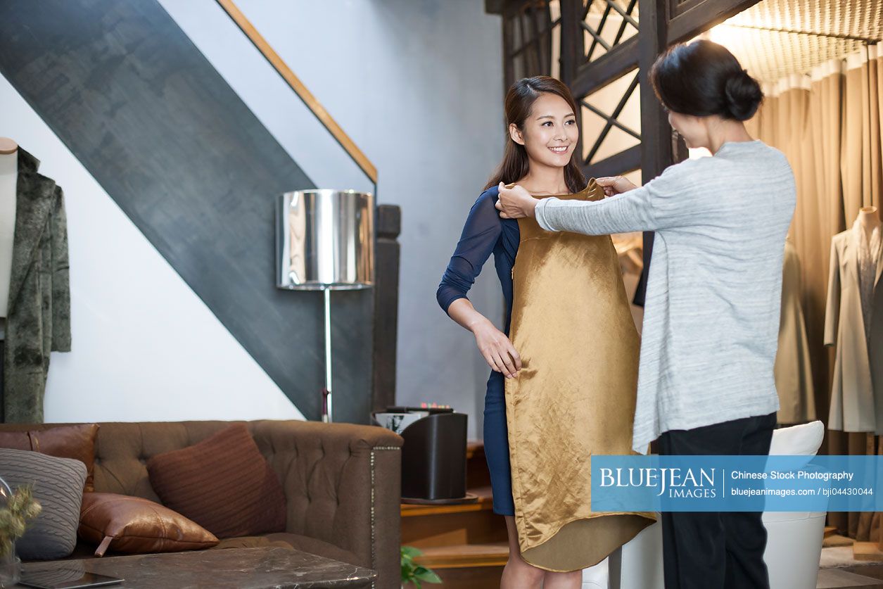 Chinese clothing store owner helping customer with choosing dress