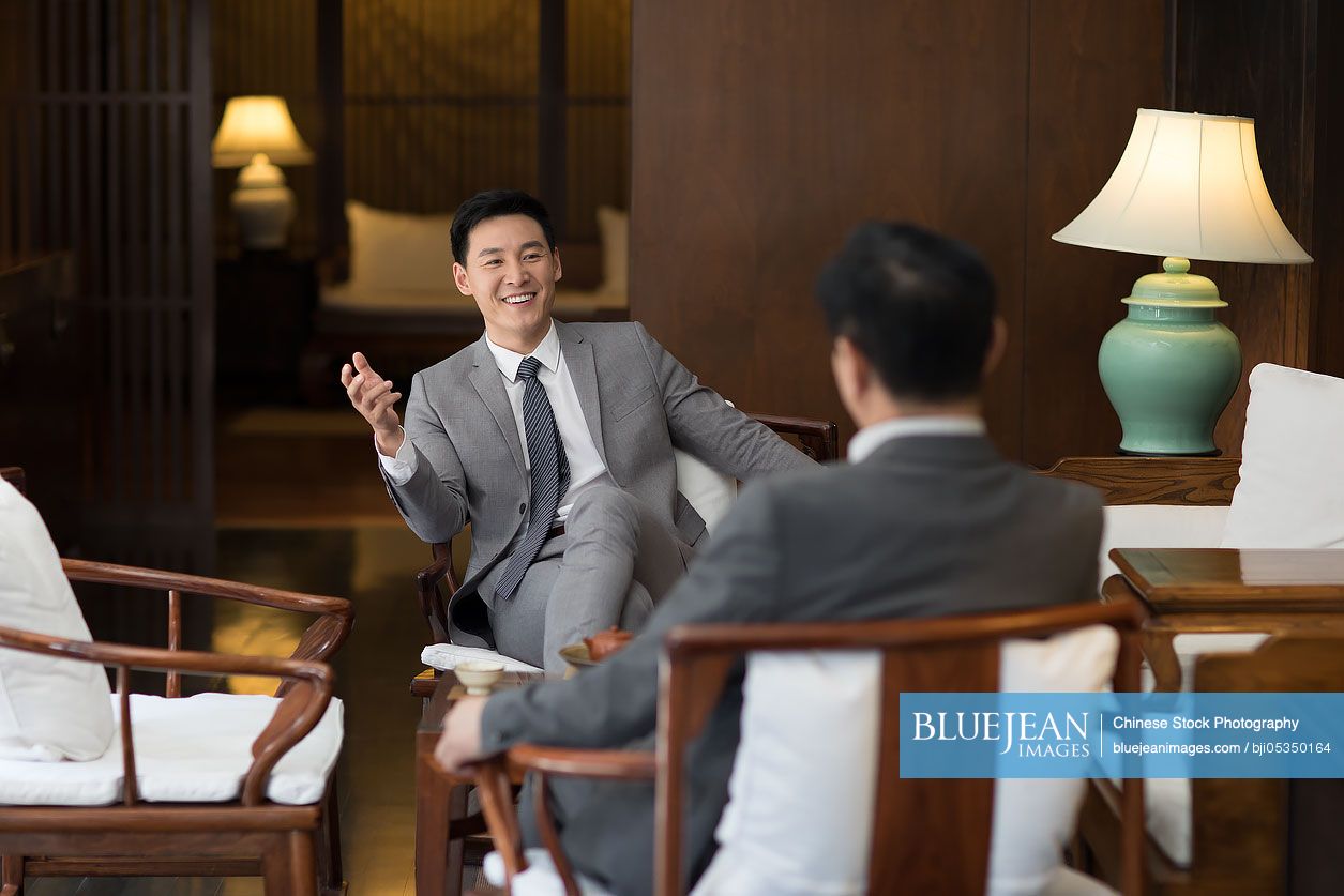 Cheerful Chinese businessmen talking in tea room